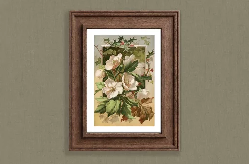A framed botanical illustration of white flowers and green leaves on a cream background, designed as a Victorian Christmas decoration, displayed on a muted green wall. The frame is dark brown with a textured finish.