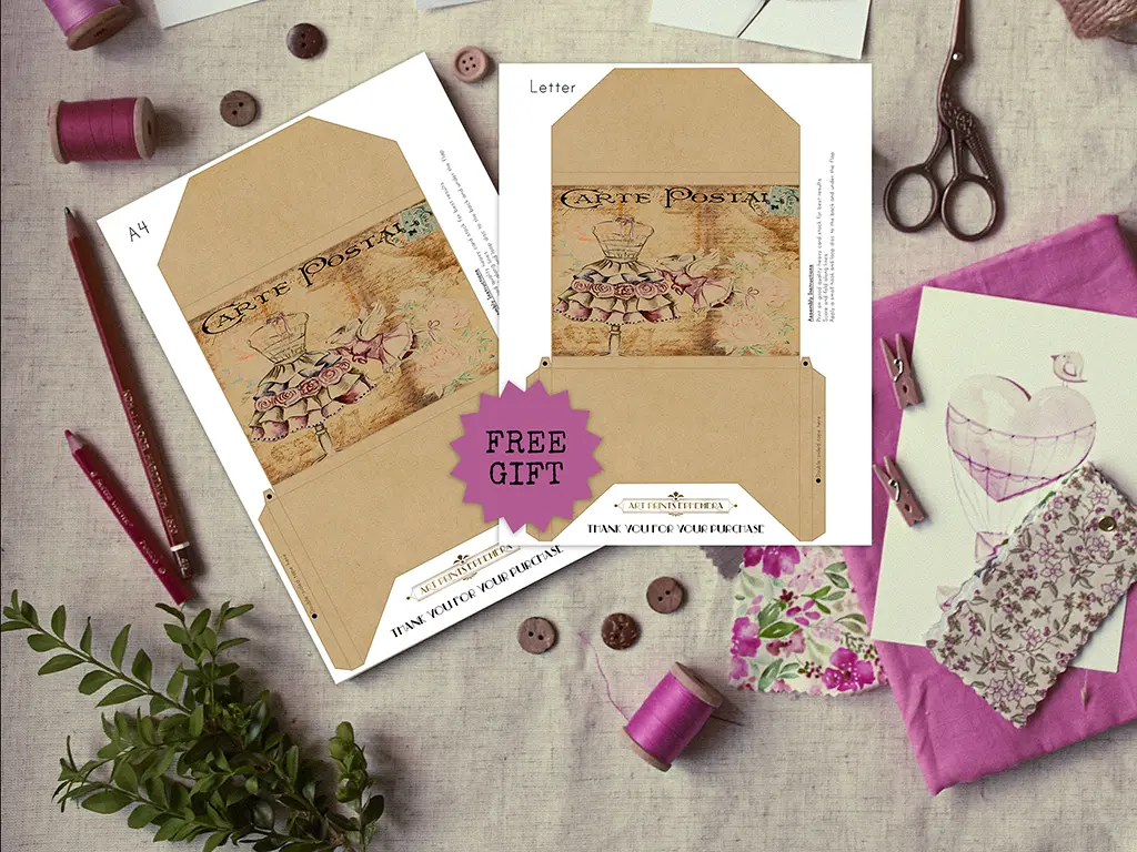 A flat lay image featuring vintage-themed stationery sets with an illustration of a cake on a stand. The sets are labeled "A4" and "Letter." Scattered around are spools of pink thread, scissors, a plant, and fabric swatches. A "FREE GIFT" sticker is on one set.